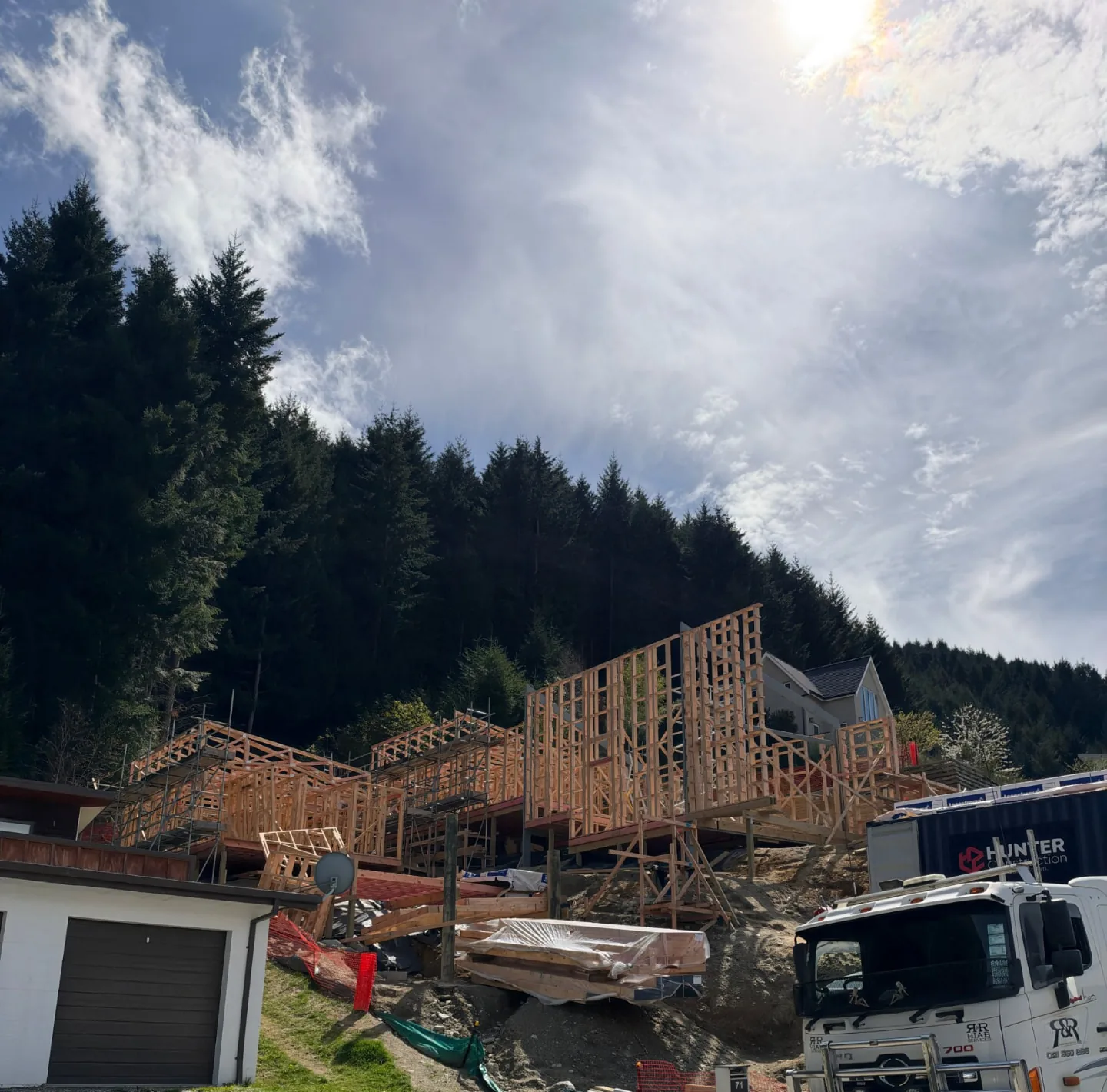 Te Tihi Villas framing on the steep Fernhill site, with the Hunter container and a Hiab truck below
