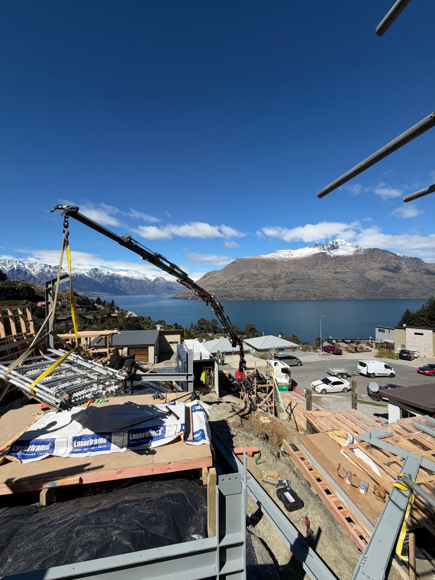 Hiab crane lifting scaffolding at Te Tihi Villas with Lake Wakatipu and the Remarkables behind
