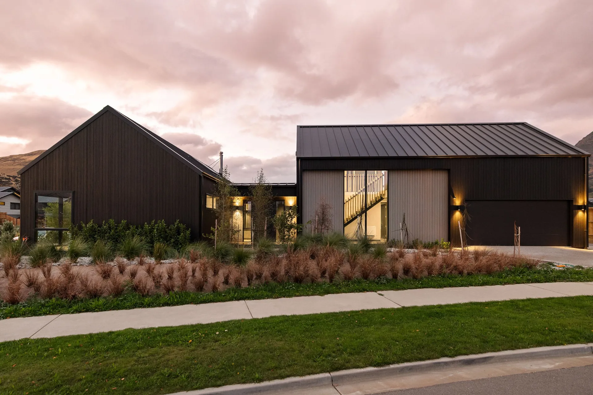 Black-clad gabled home with landscaped gardens at dusk, Drysdale Road, Queenstown