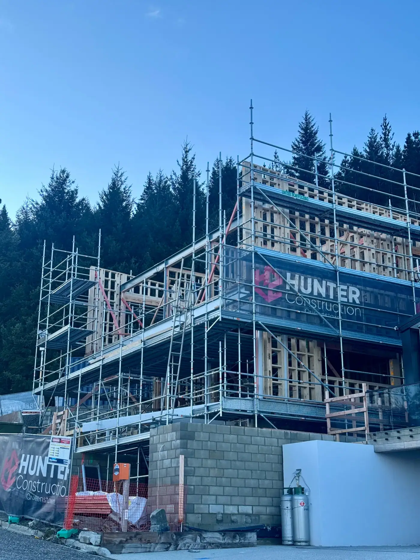 Vancouver Drive home build wrapped in scaffolding with Hunter Construction banner, Queenstown