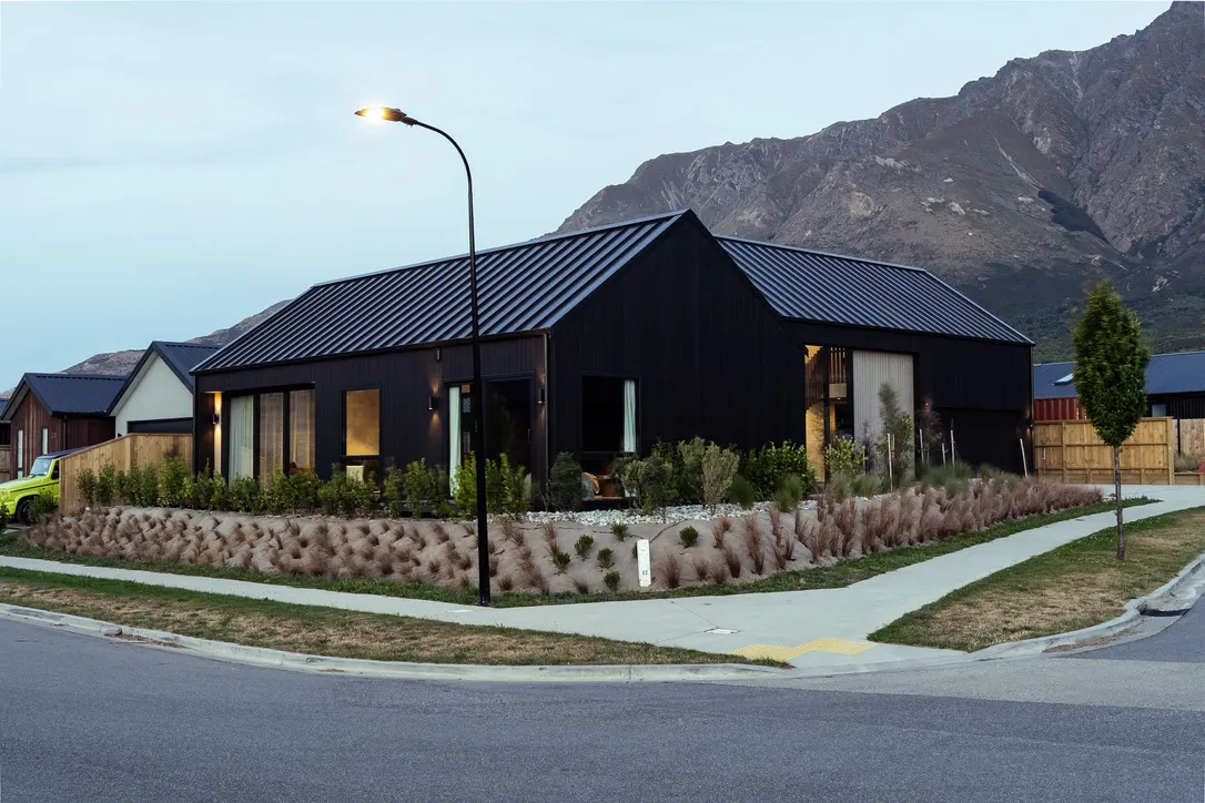 Drysdale Road black gabled home at dusk with mountain backdrop, Queenstown